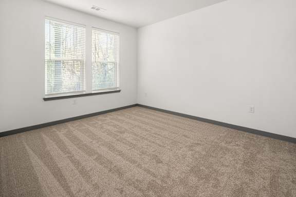 A room with a carpeted floor and a window with blinds.