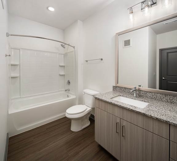 A white bathroom with a wooden floor and a white tub.