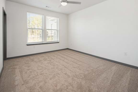 A room with a carpeted floor and a window with blinds.