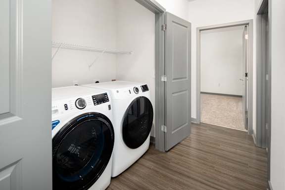 A white front load washing machine sits in a laundry room.