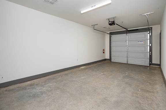 A large empty room with a white wall and a closed white door.