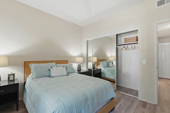 A bedroom with a bed, nightstand, and a mirror.