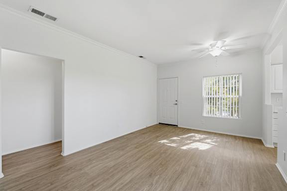 A room with wooden flooring and a window with blinds.