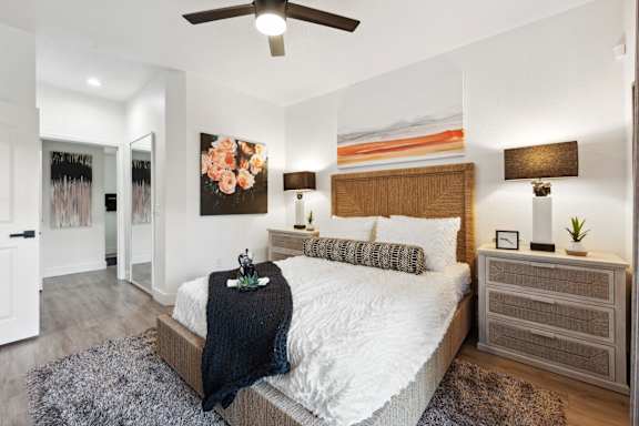 A bedroom with a bed, nightstands, and a ceiling fan.