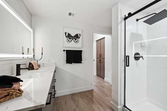 A bathroom with a white sink and a black and white picture on the wall.