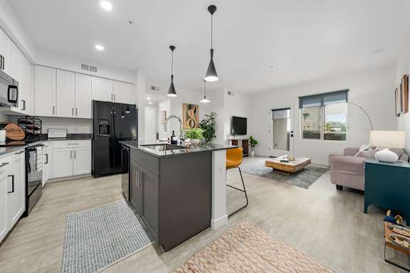 A modern kitchen with a black refrigerator and white cabinets.