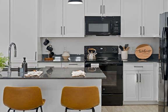 A kitchen with black appliances and white cabinets.