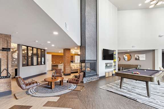A modern living room with a pool table and a fireplace.