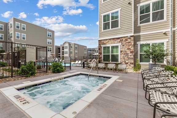 A swimming pool surrounded by lounge chairs and apartment buildings.
