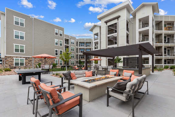 A patio with chairs and a table is surrounded by apartment buildings.