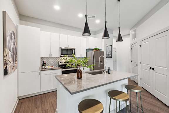 A modern kitchen with a white countertop and stools.