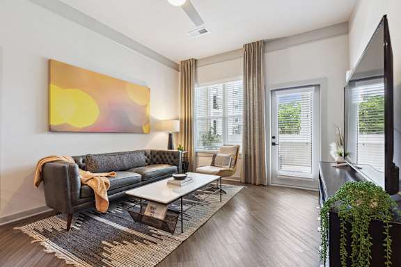 A modern living room with a grey sofa and a large abstract painting on the wall.