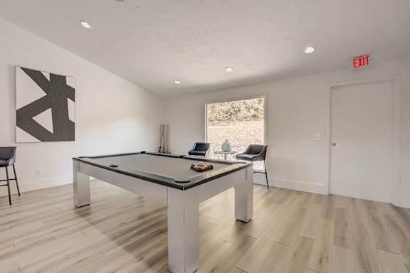 A pool table in a room with a chair and a painting on the wall.