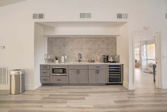 A modern kitchen with a grey backsplash and grey cabinets.
