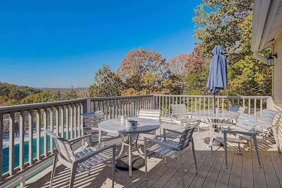 A wooden deck with a table and chairs overlooking a pool.
