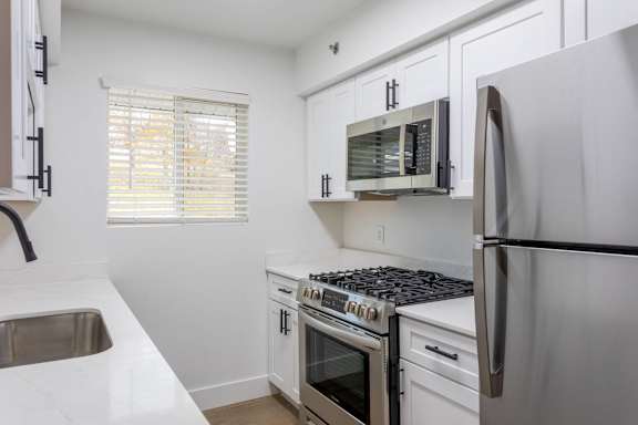 A kitchen with white cabinets and a stainless steel refrigerator.