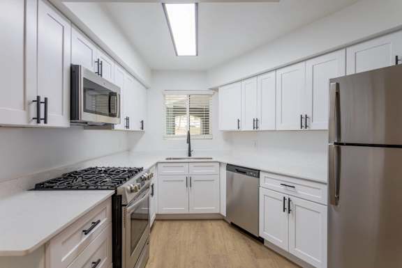 A kitchen with white cabinets and a black stove top.