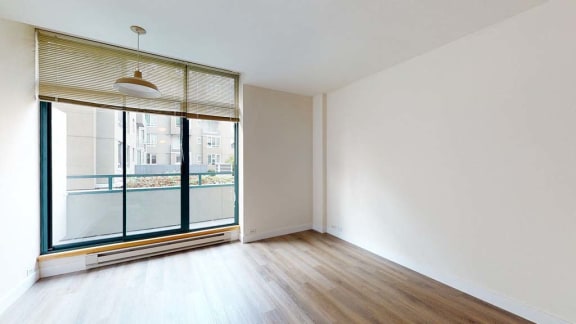 an empty room with a large window and hardwood floors