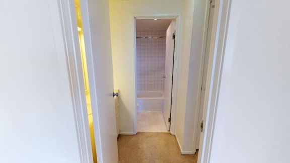 a hallway with a white toilet and a white bathtub