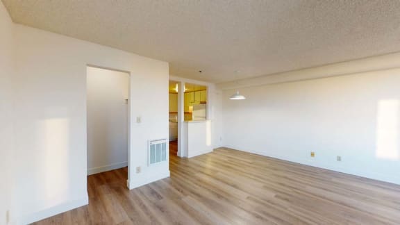 an empty living room with hardwood floors and white walls