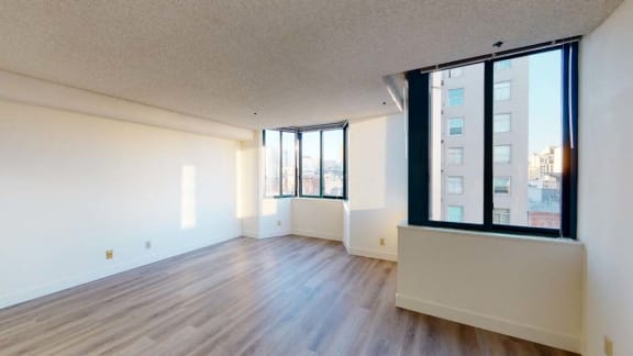 an empty living room with hardwood floors and large windows
