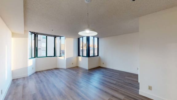 an empty living room with hardwood floors and large windows