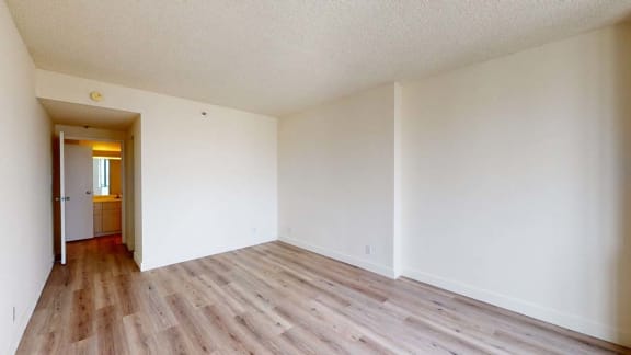 a bedroom with hardwood floors and white walls