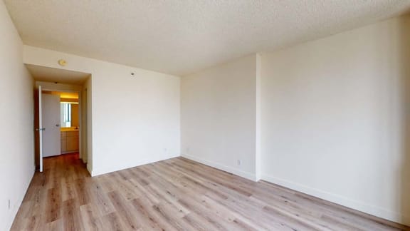 a bedroom with hardwood floors and white walls