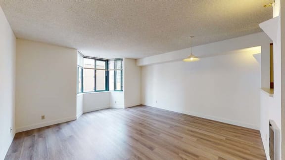 an empty living room with hardwood floors and a large window