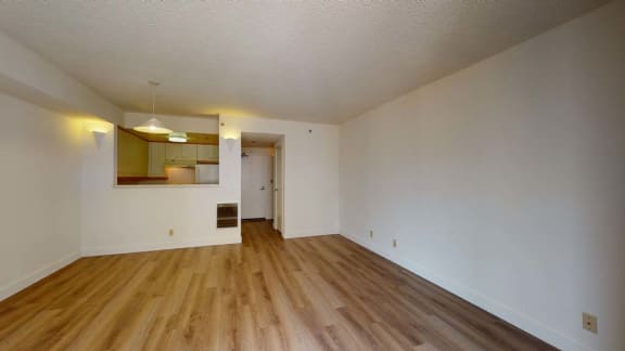 an empty living room with a hardwood floor and white walls