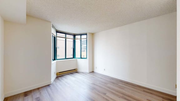 an empty room with hardwood floors and a large window