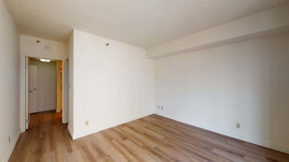 a bedroom with white walls and a wooden floor