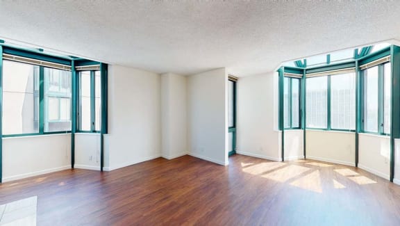an empty living room with hardwood floors and large windows