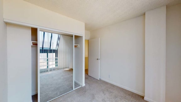 a bedroom with a mirrored door and a large window