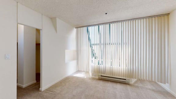 an empty room with a large window and blinds