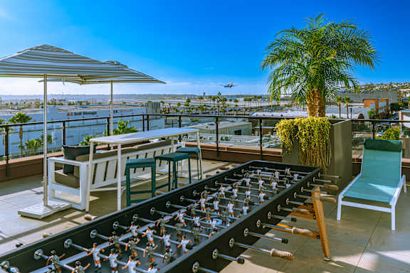 A foosball table is set up on a balcony with a view of the city.