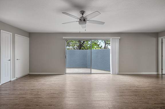 A room with a ceiling fan and sliding glass doors.