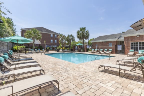 clubhouse exterior, pool, lounge chairs and blue umbrella  at Vista Commons Apartments, Columbia, SC