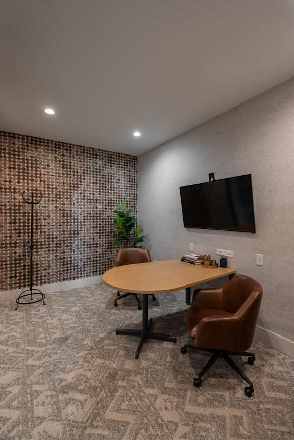 A conference room with a brown table, chairs, and a television mounted on the wall.