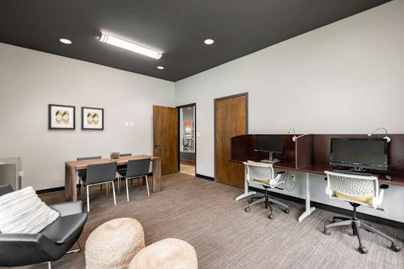 A room with a desk, chairs, and a television.