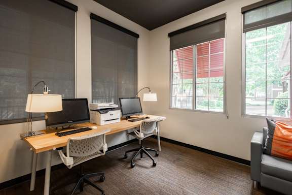 A room with a desk, chairs, and computers.