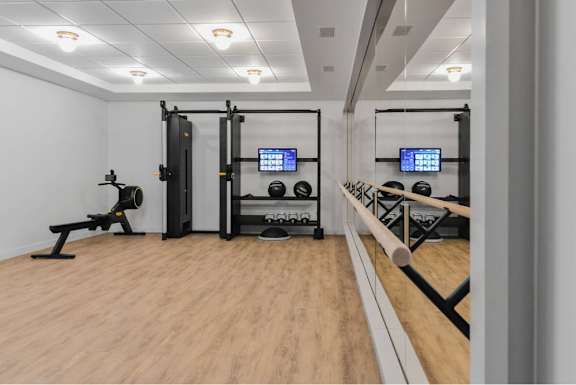 A gym with a wooden floor and various exercise equipment.