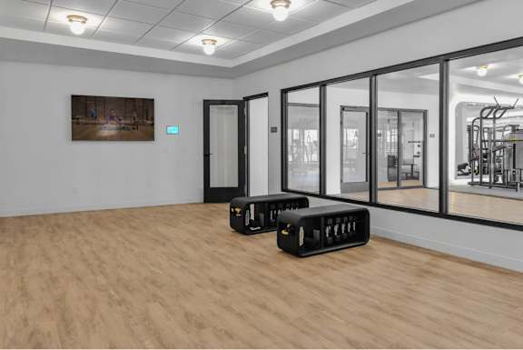 A gym with a wooden floor and a mirrored wall.