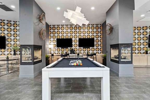 A pool table is in the middle of a room with a black and gold patterned wall.
