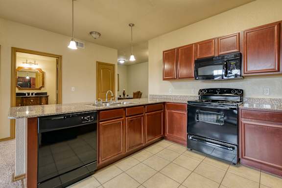A kitchen with dark wood cabinets and black appliances.