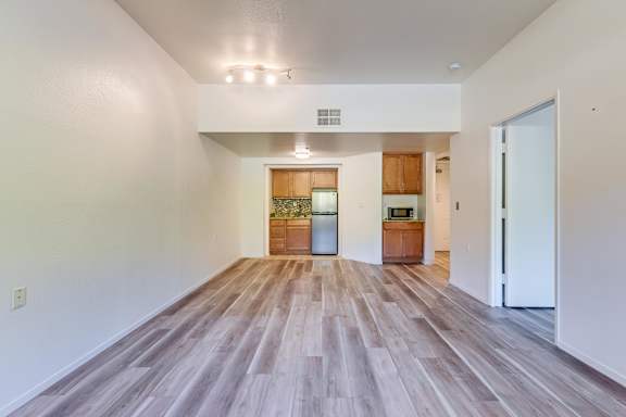 A spacious room with wooden flooring and white walls.