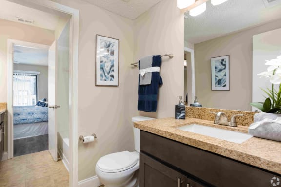 Bathroom with floating vanities, quartz countertops, backlit vanity mirror, walk-in shower with Euro shower door and quartz-topped bench seat at Seaside Villas Apartments, Pacifica SD Mgt, Florida