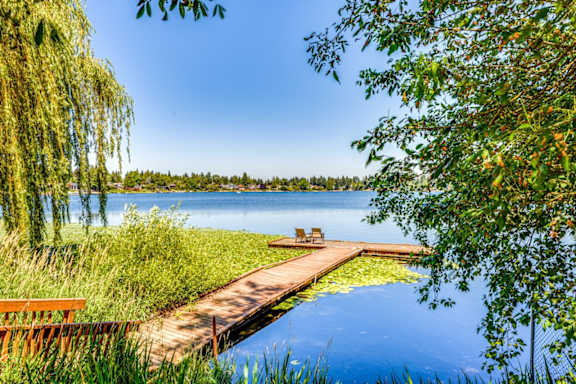 A serene lake scene with a wooden dock and benches.