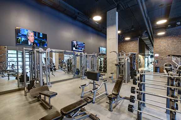 A gym with a variety of equipment including treadmills, weights, and benches. at The Mason Apartments, Chicago, IL