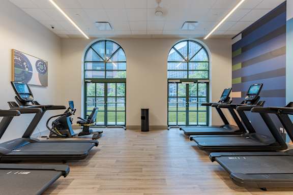 A gym with treadmills and a view of the outside.